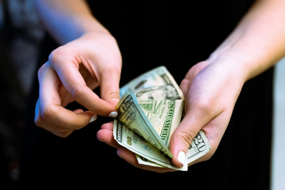 person counting twenty dollar bills: Photo by Igal Ness on Unsplash