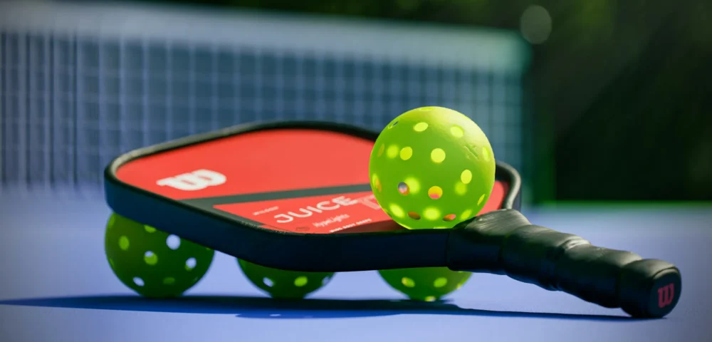 A pickleball paddle and four pickleballs: Photo by Brendan Sapp on Unsplash