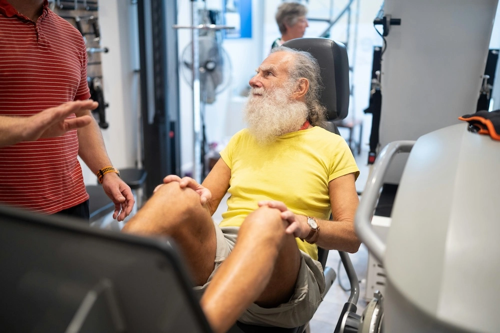 senior man exercising in a gym with a personal trainer