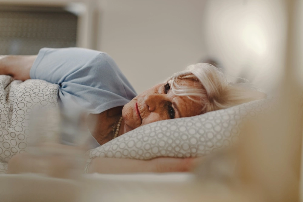 a close up view of a woman laying on her side in bed with her eyes open looking away from camera