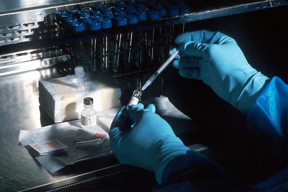 researcher in a medical lab holding syringe and vial